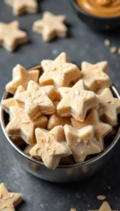 Homemade frozen yogurt and peanut butter dog treats shaped like stars in a metal bowl against dark background